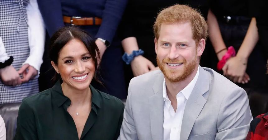 (l-r): Meghan Markle and Prince Harry smiling and attending an event.
